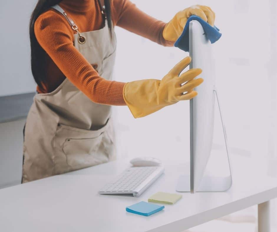 professional cleaner person cleaning computer screen in an office